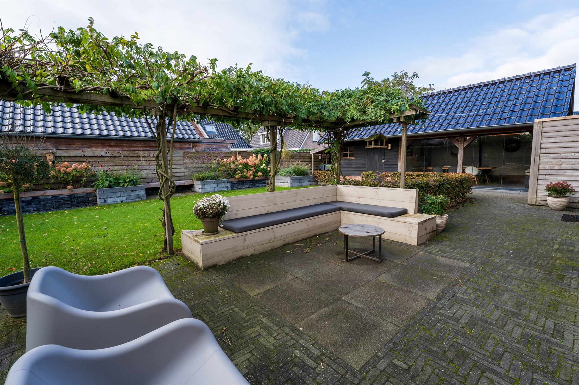 Achtertuin met pergola en loungebank